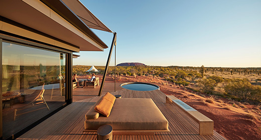 Pärchen lehnt an Baum im Abendlicht vor einem urigen Haus im Grünen