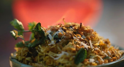 Steaming bowl of fried rice with vegetables and herbs